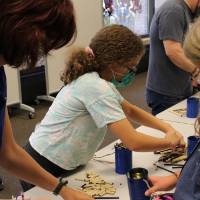 A teacher helps a student sort straws for her bee house
